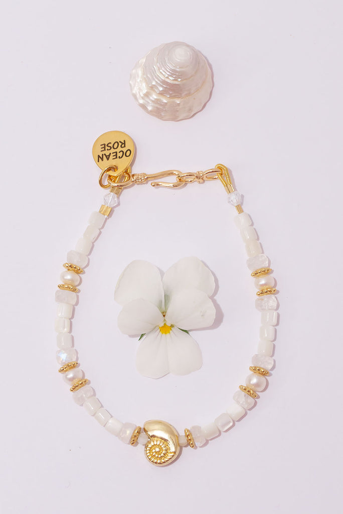 Cool white and shimmer gold make this the perfect bracelet for your next chic beachside look.