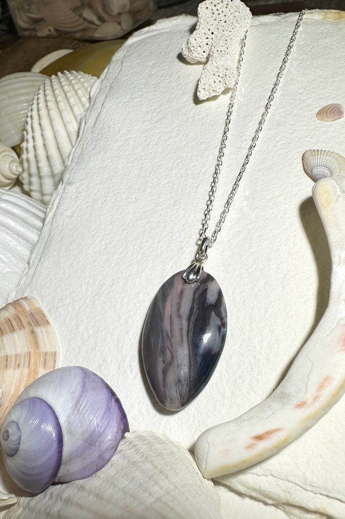 his opal pendant is a curious piece, the dark landscape has hints of pink running deep within the stone, there is a sunlight flash of green gold on the top corner, a hidden world.