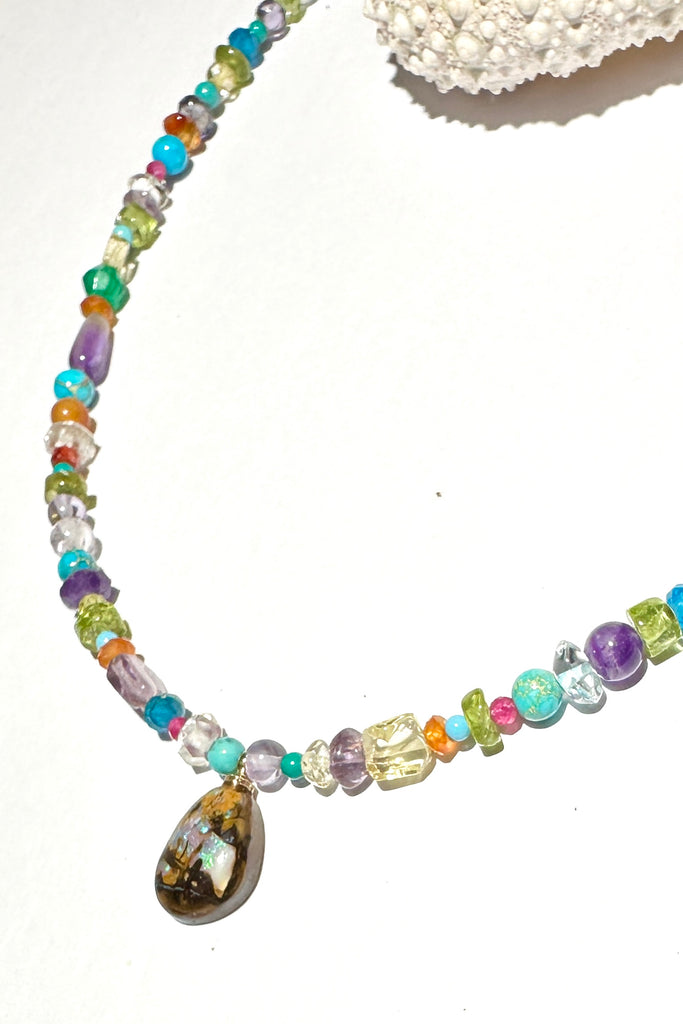 So pretty and modern, this teeny tiny opal is the centrepiece on a multi stone bead gemstone necklace that sparkles in the light.&nbsp;  This Australian opal has a pool of earthy blueish mauve down the centre. The necklace is made from many gemstone seed beads, including natural Turquoise, Howlite, Amethyst, Citrine, Flourite,Carnelian and more.