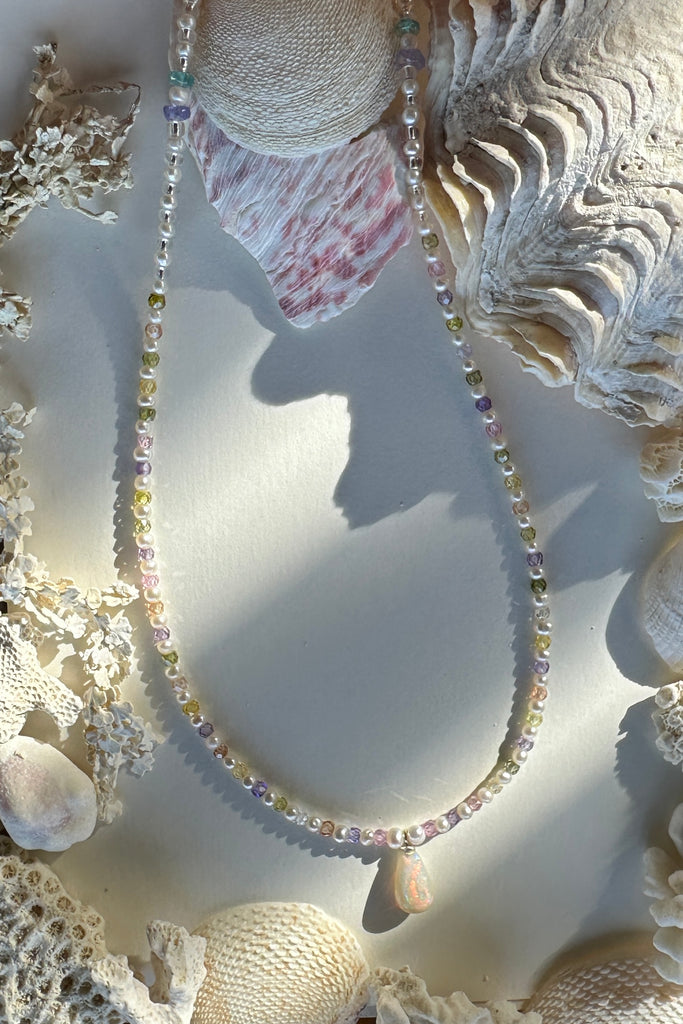 Freshwater pearls.
Solid Australian crystal opal centrepiece in swirling red, green, blue and gold.

All freshwater pearls will all have interesting irregularities.