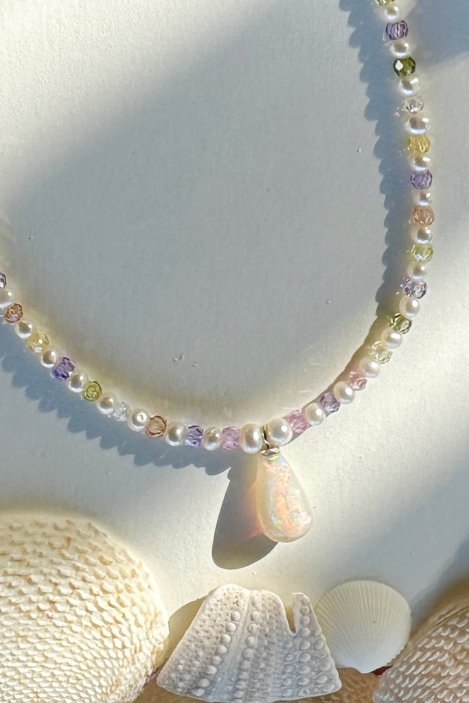 Freshwater pearls.
Solid Australian crystal opal centrepiece in swirling red, green, blue and gold.

All freshwater pearls will all have interesting irregularities.