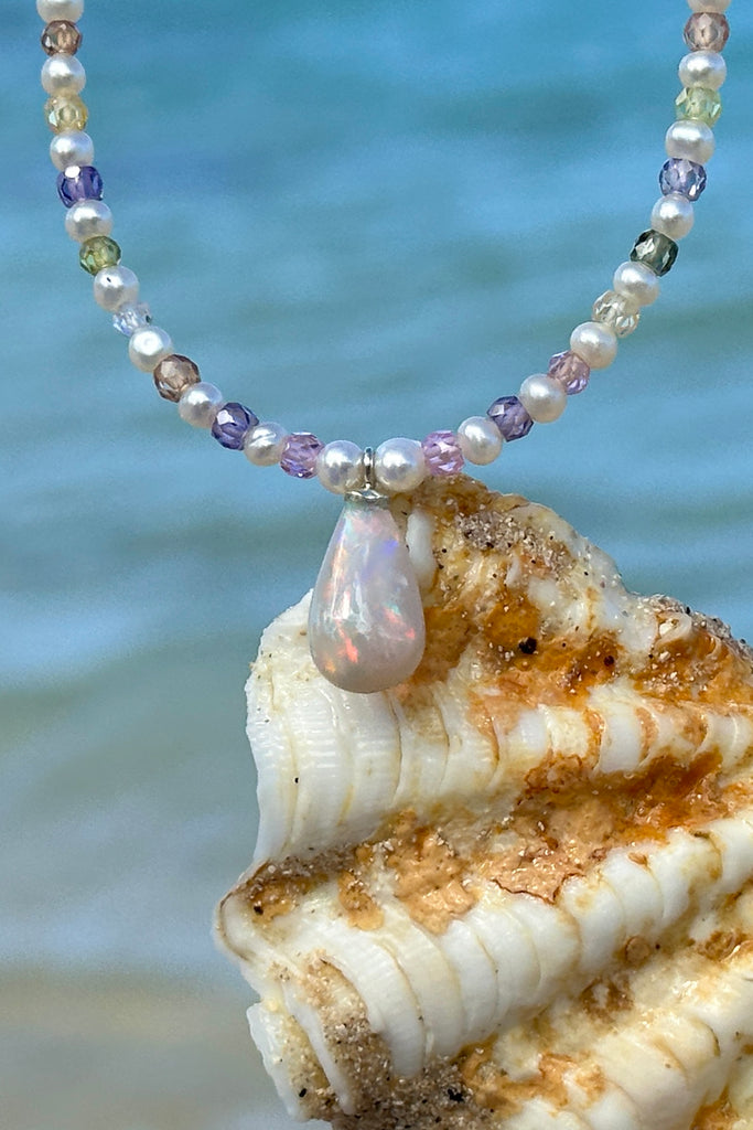 Freshwater pearls.
Solid Australian crystal opal centrepiece in swirling red, green, blue and gold.

All freshwater pearls will all have interesting irregularities.