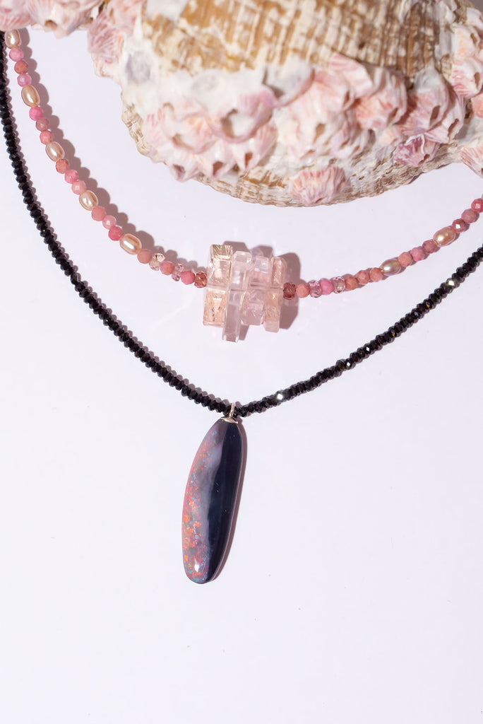 Discover the magic of Australian Black Opals. This incredibly chic necklace features a mesmerising organic cut opal with brilliant red, pink &amp; gold colour play.