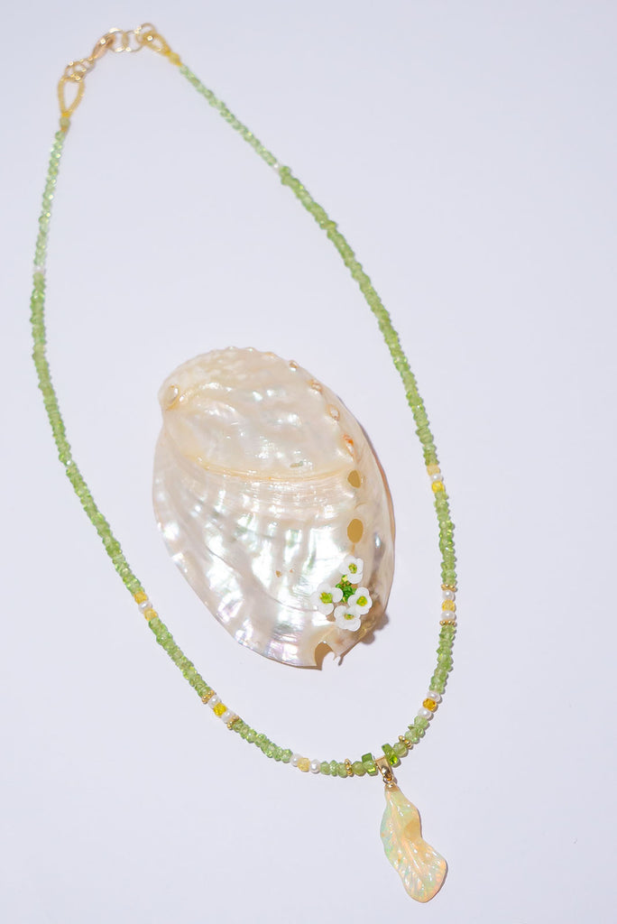 Feel the magic of this beautiful crystal opal carved into a feather, glowing green, blue, pink and gold this ethereal piece comes on a necklace of soft green Peridot beads with Citrine and pearl highlights.