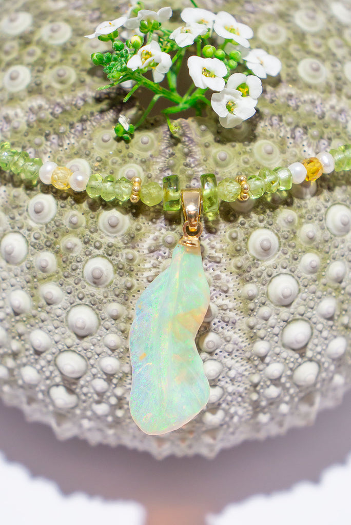 Feel the magic of this beautiful crystal opal carved into a feather, glowing green, blue, pink and gold this ethereal piece comes on a necklace of soft green Peridot beads with Citrine and pearl highlights.