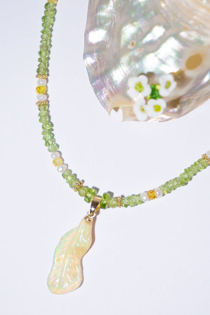 Feel the magic of this beautiful crystal opal carved into a feather, glowing green, blue, pink and gold this ethereal piece comes on a necklace of soft green Peridot beads with Citrine and pearl highlights.