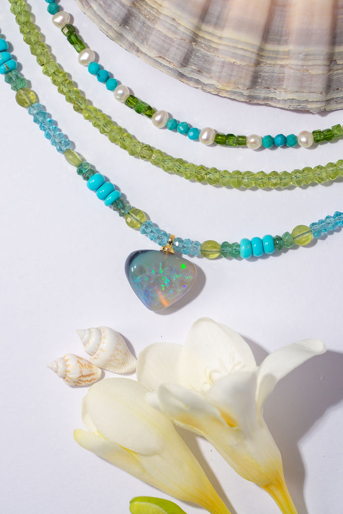 Like waters swirling around outskirts of a tropical reef this captivating necklace features enchanting shades of blue and sea green and the gorgeous semi black opal pendant adds a touch of magic.