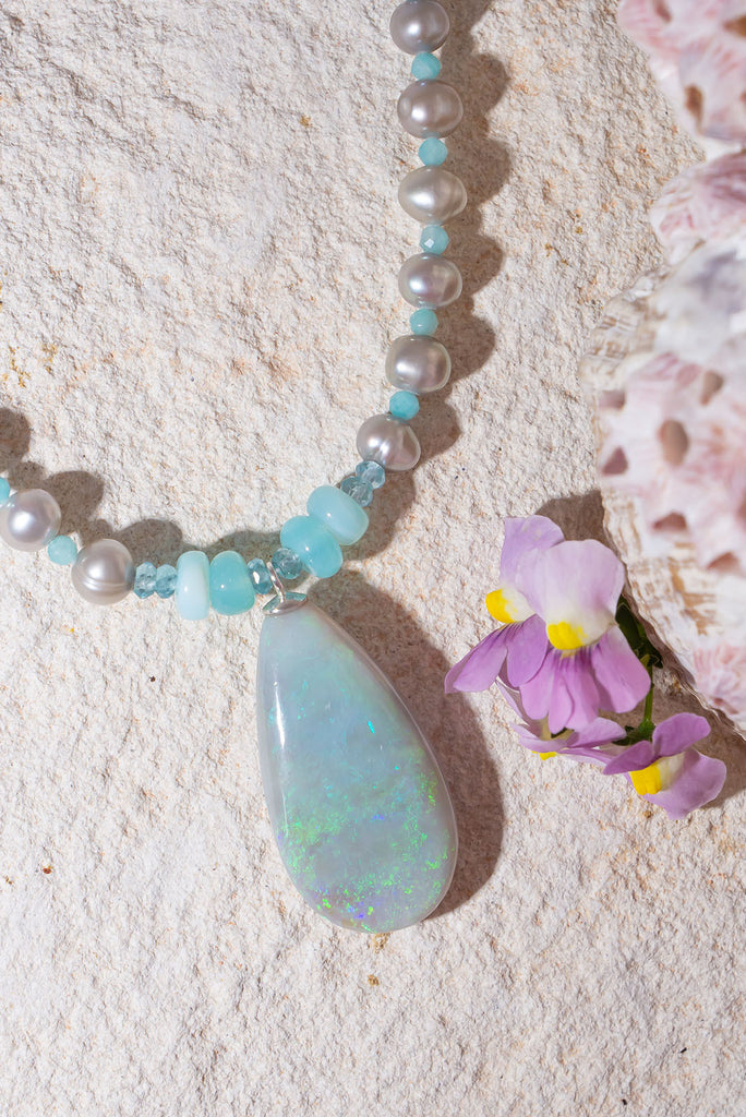 Like the colour of a wave as it turns, a crystal opal with tiny sparkle flashes of green and blue, on a necklace of small lustrous silver grey pearls with Amazonite highlights.