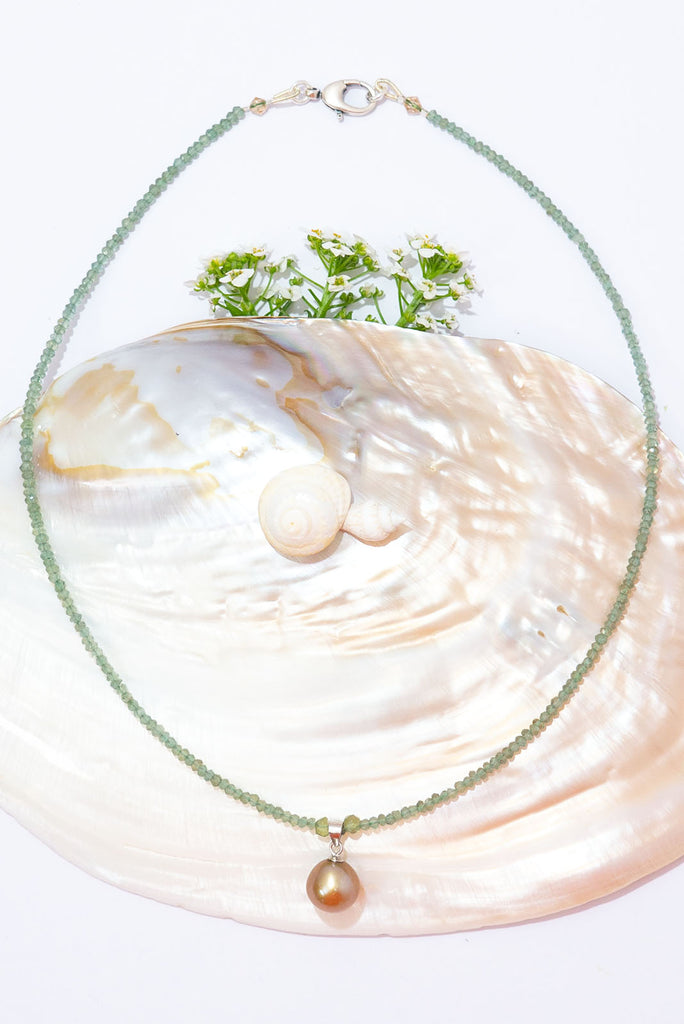 A gorgeous deep champagne pearl sits amongst a sparkling strand of mossy green apatite.