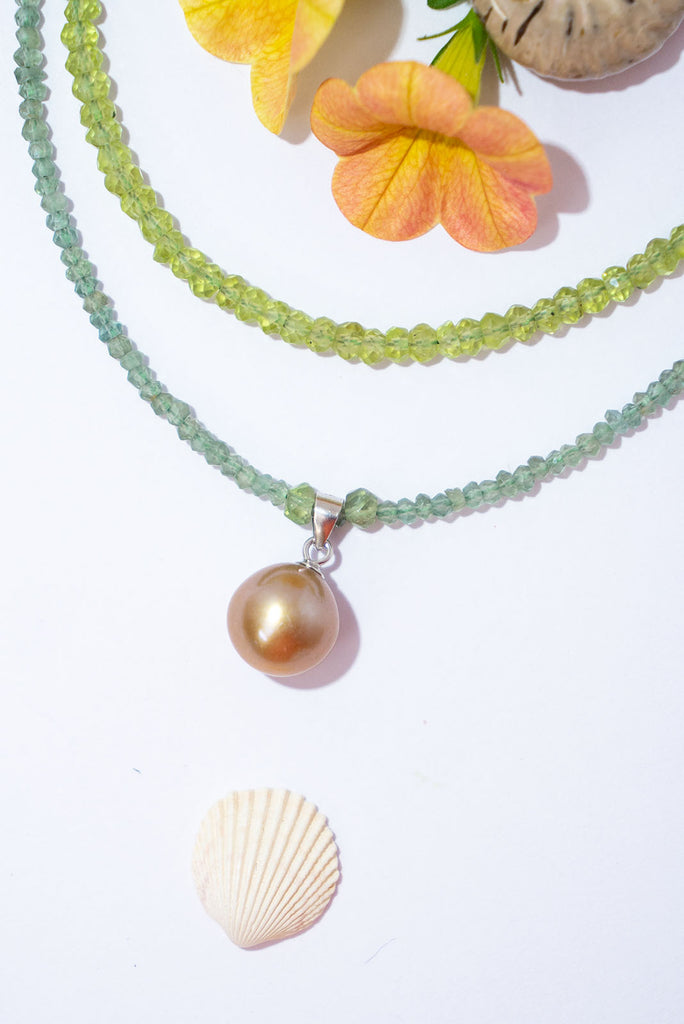 A gorgeous deep champagne pearl sits amongst a sparkling strand of mossy green apatite.