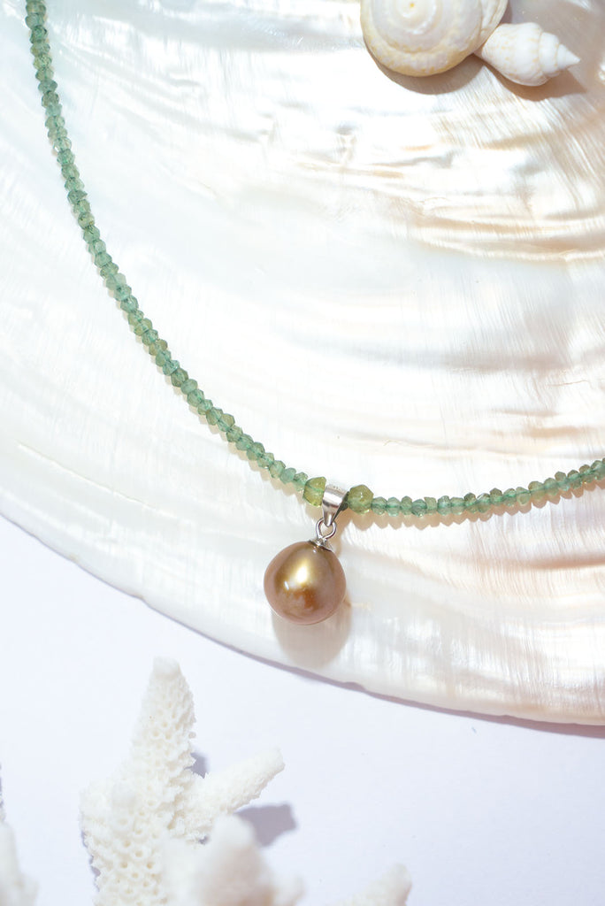 A gorgeous deep champagne pearl sits amongst a sparkling strand of mossy green apatite.