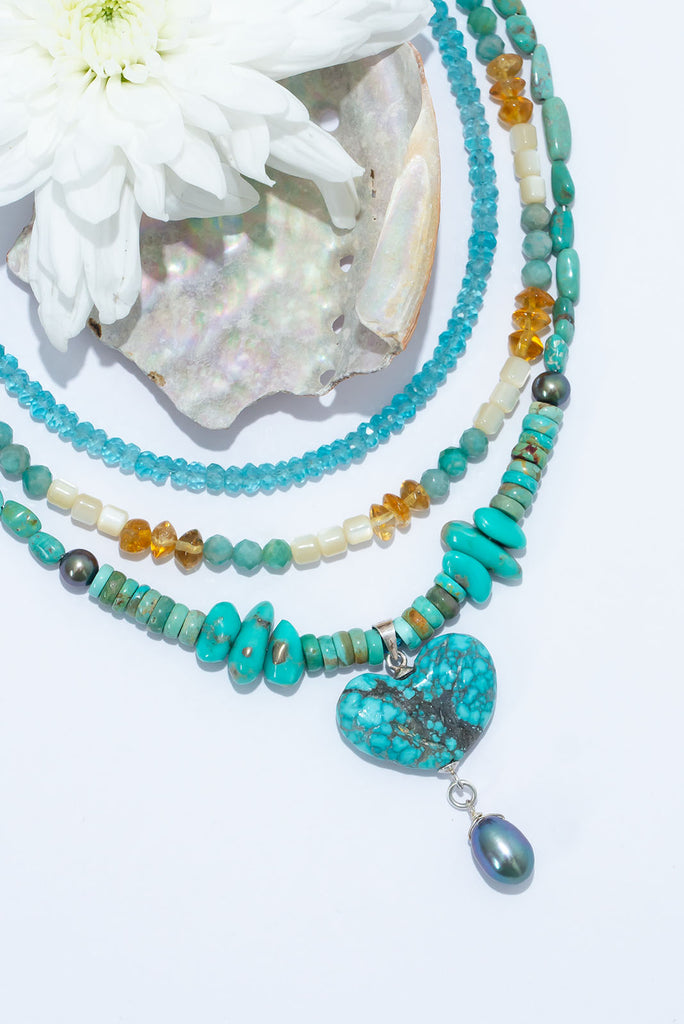 Designed and made in Noosa, a natural Turquoise heart hangs from a river of beads in all shapes and sizes. A silvery grey pearl is suspended from the heart to move when you do.