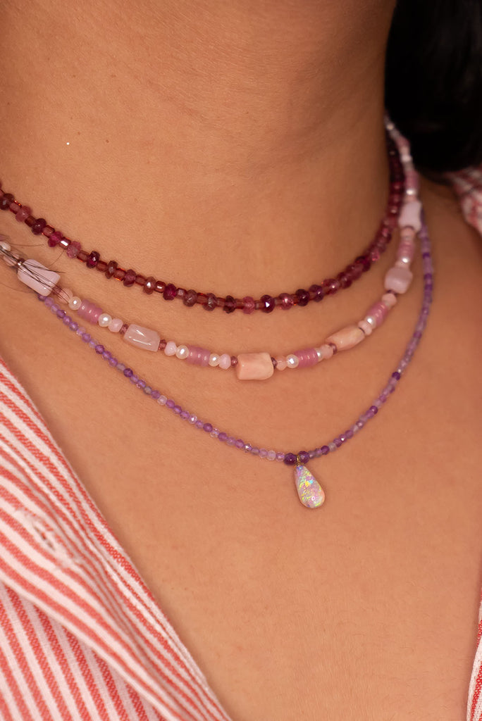 The most perfect tiny drop of crystal opal colours, it hangs from a faceted Amethyst bead gemstone necklace that sparkles in the light.
