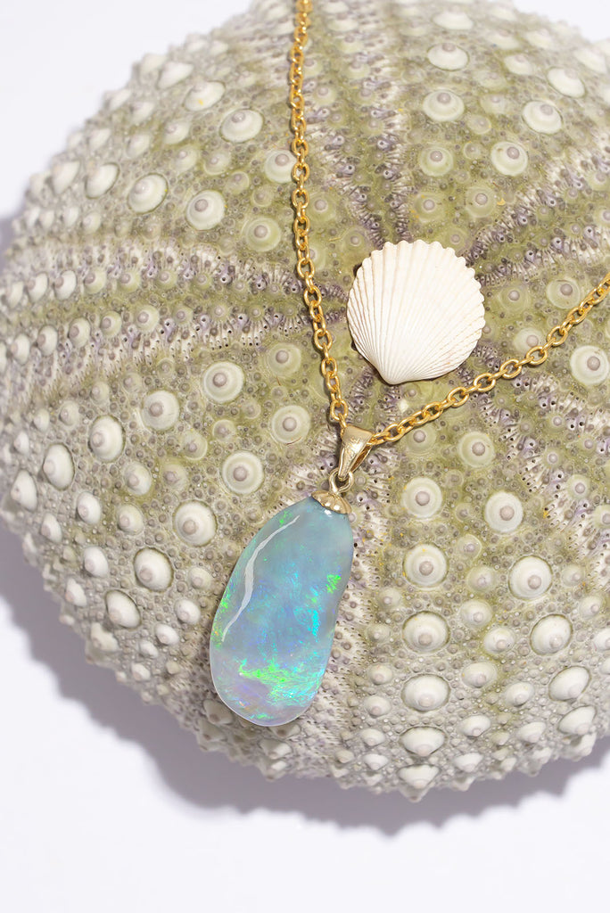 A stunning opal pendant with swirling waves of bright green, mauve and blue, the swirls accented with some gentle hand carving to highlight the swell.