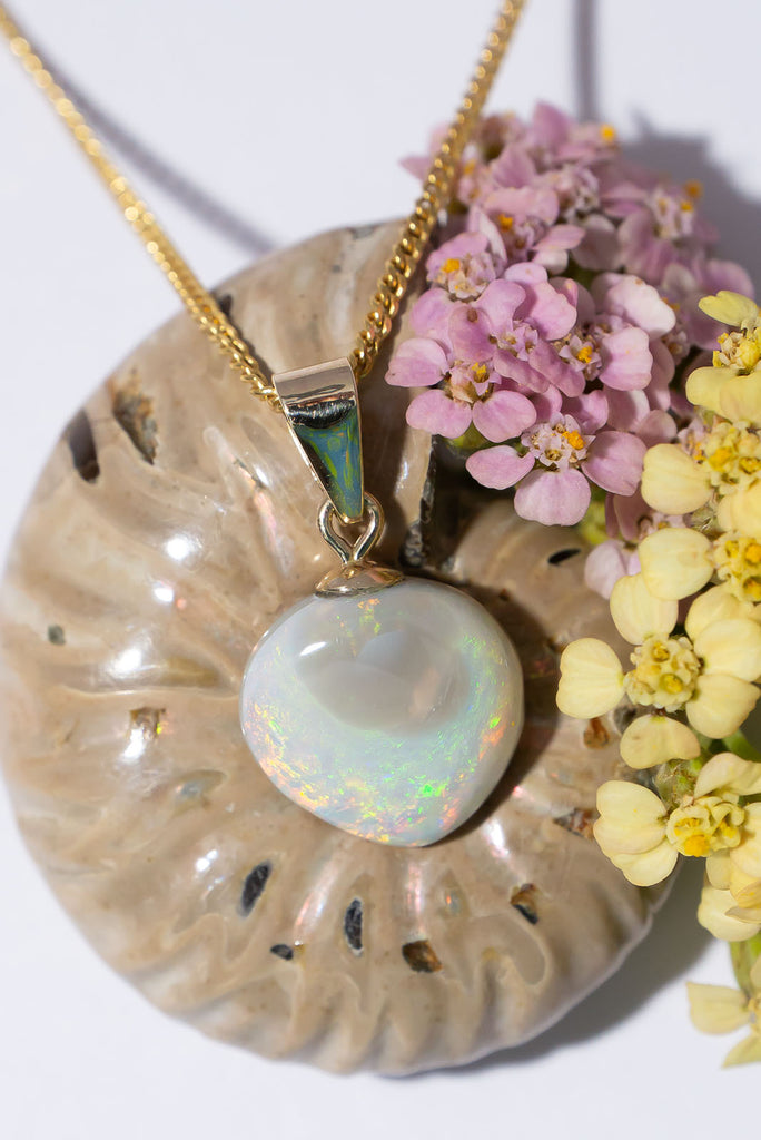 A delicate drop of white grey opal that shimmering with sparkling green fire.