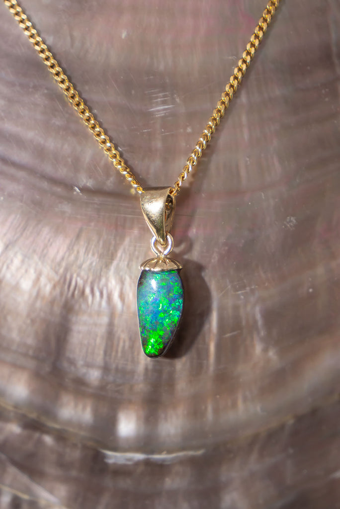 A sparkling delicate droplet of gorgeous boulder opal that shimmers with green and dark blue fire.