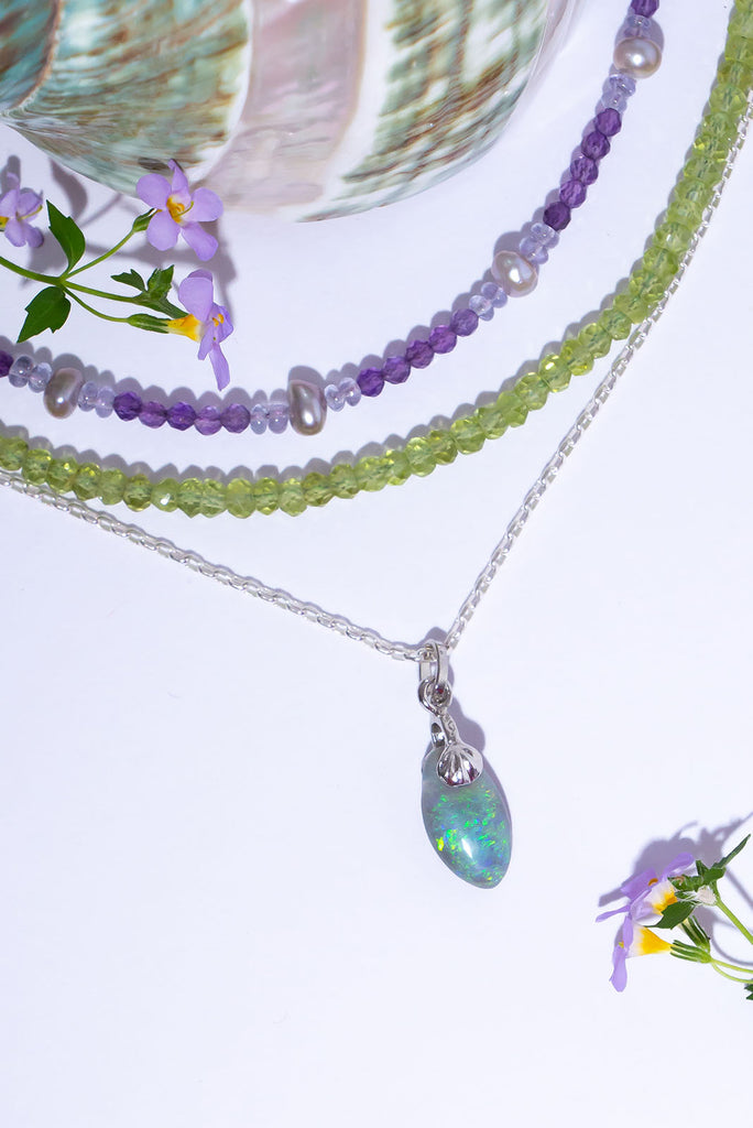 A beautiful droplet of Australian Opal with a sparkling swirl of green colour play with flecks of blue & gold.