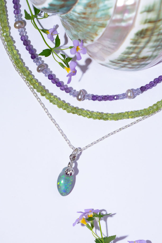 A beautiful droplet of Australian Opal with a sparkling swirl of green colour play with flecks of blue & gold.