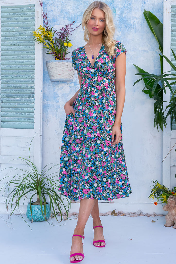 The Lizzie Ink Flower Farm Dress is a stunning midi dress with a black base and all over pink, blue and white floral print. The dress features cap sleeves, a deep v neckline, fitted Basque waist with gathered bust, elastic shirring at back waist, side pockets and is made from woven 100% rayon.