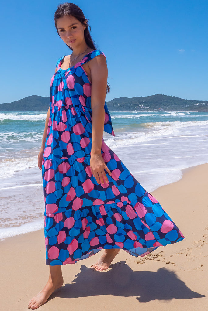 The Lovelu Blue Spots Maxi Dress is a stunning tiered maxi dress with a navy base and blue and pink zinzi spot print. The dress features an adjustable tie back neckline, tiered skirt and side pockets. Made from woven 100% rayon.